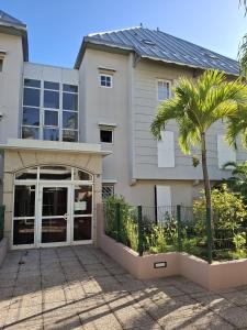a house with a palm tree in front of it at Appartement la marine in Saint-Leu