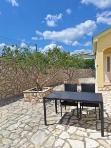a black picnic table and two chairs on a stone patio at Apartments Mikecin in Novigrad Dalmatia