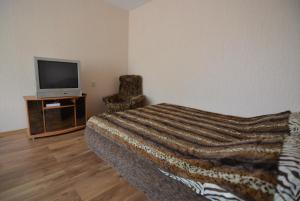 a bedroom with a bed and a tv and a chair at Airites street apartment in Liepāja