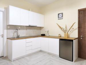 a kitchen with white cabinets and a black dishwasher at Sokrates Apartments in Preveza