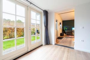 WeiteveenにあるLuxe Hottub Huisje Bij het Veen op de rand van het Bargerveen Drentheの大きな窓と廊下のある空の部屋