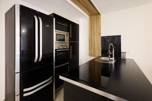 a kitchen with a black refrigerator and a sink at La Terrasse du Bonheur in Le Mans +1 photo