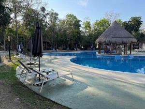 a swimming pool with chairs and an umbrella and a gazebo at Casa Xíinbal in Puerto Morelos