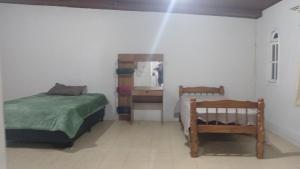 a small bedroom with two beds and a mirror at Casa Glória macaé in Macaé