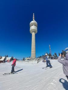 Un grupo de personas en esquís frente a una torre. en Апартаменти Pamporovo Dream в Гранд Ризорт Пампорово, en Pamporovo