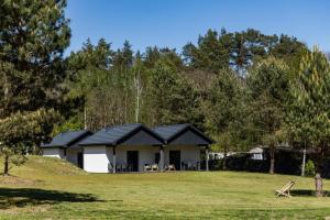 a house with a black roof in a field at Camping skansen Zdbice - domek letniskowy 1 in Zdbice