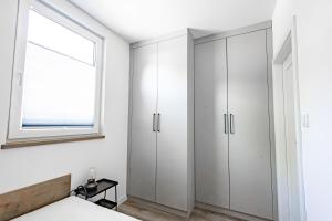 a bedroom with white cabinets and a window at Camping skansen Zdbice - domek letniskowy 1 in Zdbice