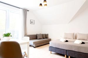 a white living room with a bed and a couch at Przy Plaży in Karwia