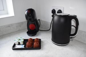 a tea kettle and a tray of cupcakes next to a coffee pot at Tolson Court House in Fazeley