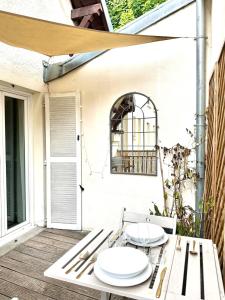 zwei weiße Teller auf einem Tisch auf einer Terrasse in der Unterkunft LE LAVADIÈRE - Joli duplex avec terrasse in Sèvres