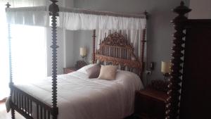a bedroom with a canopy bed with white sheets and pillows at Casa Turistica Termas aparcamiento y desayuno incluido in Merida