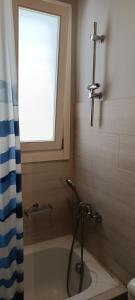 a bathroom with a bath tub with a window at Andros Guesthouses in Andros
