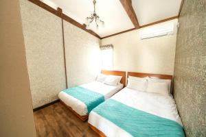 Dos camas en una habitación pequeña con en あかばなのさと, en Isla Miyako