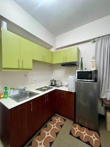 eine Küche mit grünen Schränken und einem Kühlschrank aus Edelstahl in der Unterkunft Elevated Staycation BGC Venice Grand Canal in Manila + 14 Fotos