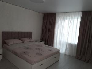 a bedroom with a bed and a large window at Люкс апартаменты -Центр in Mykolaiv