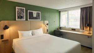 a bedroom with a white bed and a window at Campanile NATURE Les Ulis in Les Ulis