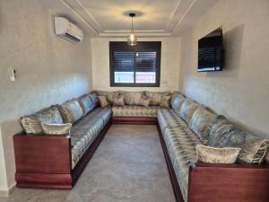 ein Wohnzimmer mit einem großen Sofa in einem Zimmer in der Unterkunft Saïdia Residence A - à 7 min de la plage in Saidia 