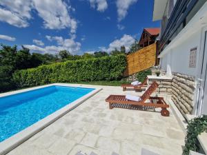 a backyard with a swimming pool and a patio with chairs and a table at Villa Otto - Private Pool & Garden in Zagreb