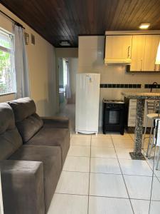 a living room with a couch and a kitchen at Chalé Blumenau in Blumenau