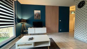 a living room with a white table and a tv at F3 proche Deauville Piscine in Touques
