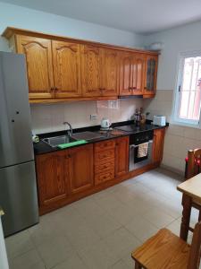 Una cocina con gabinetes de madera y un refrigerador de acero inoxidable. en Dúplex Casa Nerea, en Santa Cruz de la Palma