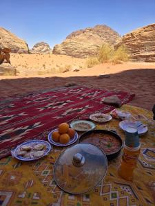 a table with plates of food in the desert at Wadi Rum Desert Experience in Wadi Rum