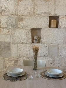 a table with two plates and a vase of grass at Civico 39 in Ostuni