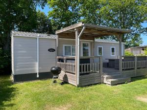 a cabin with a porch and a grill in a yard at Chalet JT08 in Renesse in Renesse