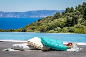 a pile of blankets and pillows next to a body of water at Villa Mavraki in Glossa