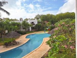 a swimming pool with benches and umbrellas next to a house at Green Malindi Luxury Apartments in Malindi