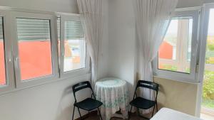 two chairs and a table in a room with windows at Pension Lopez in Fisterra