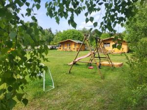 a playground in a field with a house in the background at Leśnisko in Niegowa