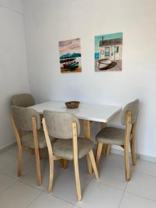 a dining room table with four chairs and paintings at Villa Oliver in Hamallë