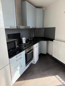 eine Küche mit weißen Schränken und schwarzen Arbeitsplatten in der Unterkunft Séjour à Paris in Aubervilliers