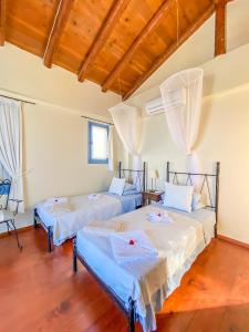two beds in a room with wooden floors at Kyparissis Beach house 1 in Lésvos