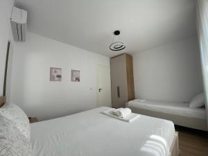 a white bedroom with two beds and a lamp at Villa Oliver in Hamallë