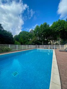 a blue swimming pool with a fence and trees at Studio des Anges #2 in Sauve +13 photos