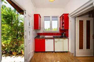 a kitchen with red and white cabinets and a window at Apartmani Tinka in Starigrad