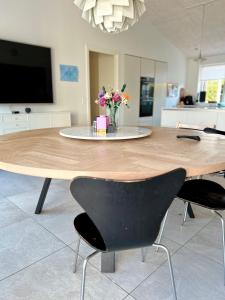 ein Holztisch mit Stühlen und einer Vase mit Blumen in der Unterkunft Spacious City Family Retreat With Garden & Patio in Odense