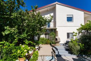 a white building with trees and plants in front of it at Apartmani Tinka in Starigrad