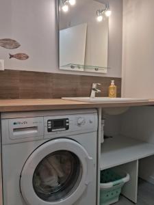 a laundry room with a washing machine under a counter at Le 46 pour 2 personnes in Crots