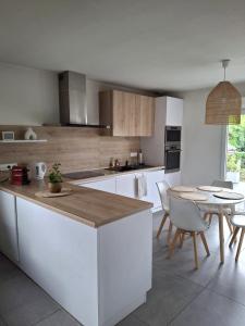 a kitchen with white cabinets and a table with chairs at Maison 5 personnes in Lutterbach