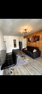 a living room with a black couch and a table at Appartement avec vue montagne in Briançon