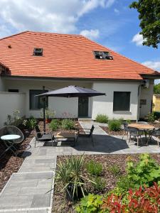 a patio with an umbrella and tables and chairs at Kastélykert Vendégház Tata in Tata