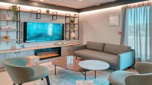 a living room with a couch and a tv at Campanile NATURE - Dreux in Dreux