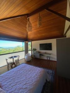 a bedroom with a bed and a table and a tv at Sítio Morro do Balaio in Guarapari
