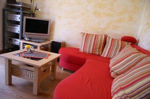 sala de estar con sofá rojo y TV en Emkendorf - An den Teichen, en Emkendorf