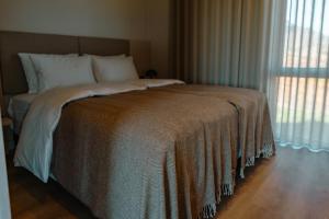 uma cama num quarto com uma grande janela em Peninsula Suites em Hellnar