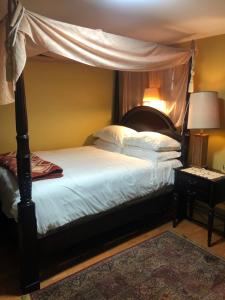 una camera con letto a baldacchino con lenzuola e cuscini bianchi di A secluded bedroom with a private full bathroom a Chicago