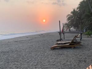 a bench on the beach with the sunset in the background at Cocobeach Palomino in Palomino